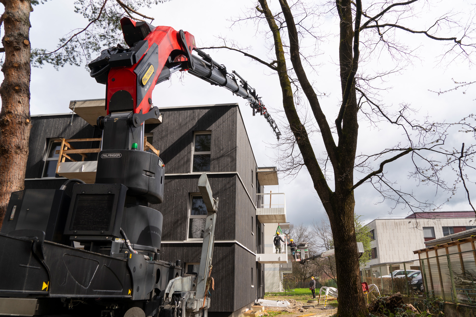 Balkongeländerteile müssen sicher über das Mehrparteienhaus gehoben werden – eine Aufgabe, die der PK 580 TEC souverän meistert. 