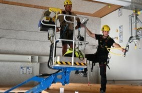 AST-Trainer Jan Bauer zeigt, wie der Einstieg in einen Arbeitskorb in luftiger Höhe vollzogen werden muss - die Sicherung an einem Anschlagspunkt bleibt so lange bestehen, bis eine Verbindung zum Höhensicherungsgerät im Arbeitskorb hergestellt ist.