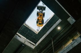  Der Radlader L120 Electric wird von einem Kran zentimetergenau in 26 Meter Tiefe herabgelassen.