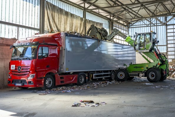 Der SENNEBOGEN 340 G verlädt mit seinem Teleskoparm mühelos Abfall in einen LKW.
